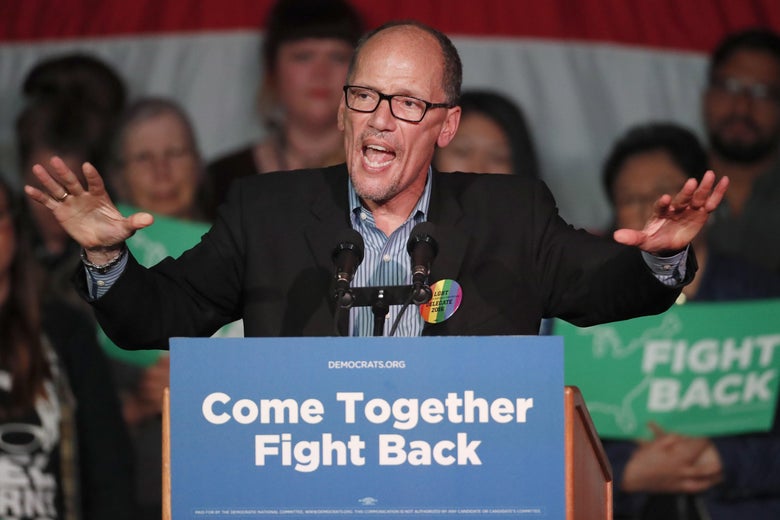 DNC Chairman Tom Perez holds his arms up as he speaks in front of a podium at a rally